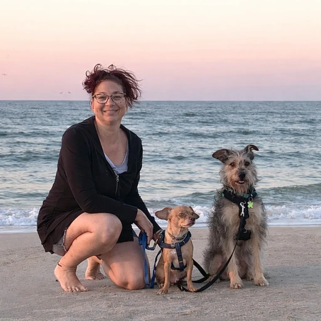 Andrea, professional dog trainer, with trained dogs on Virginia Beach at sunset